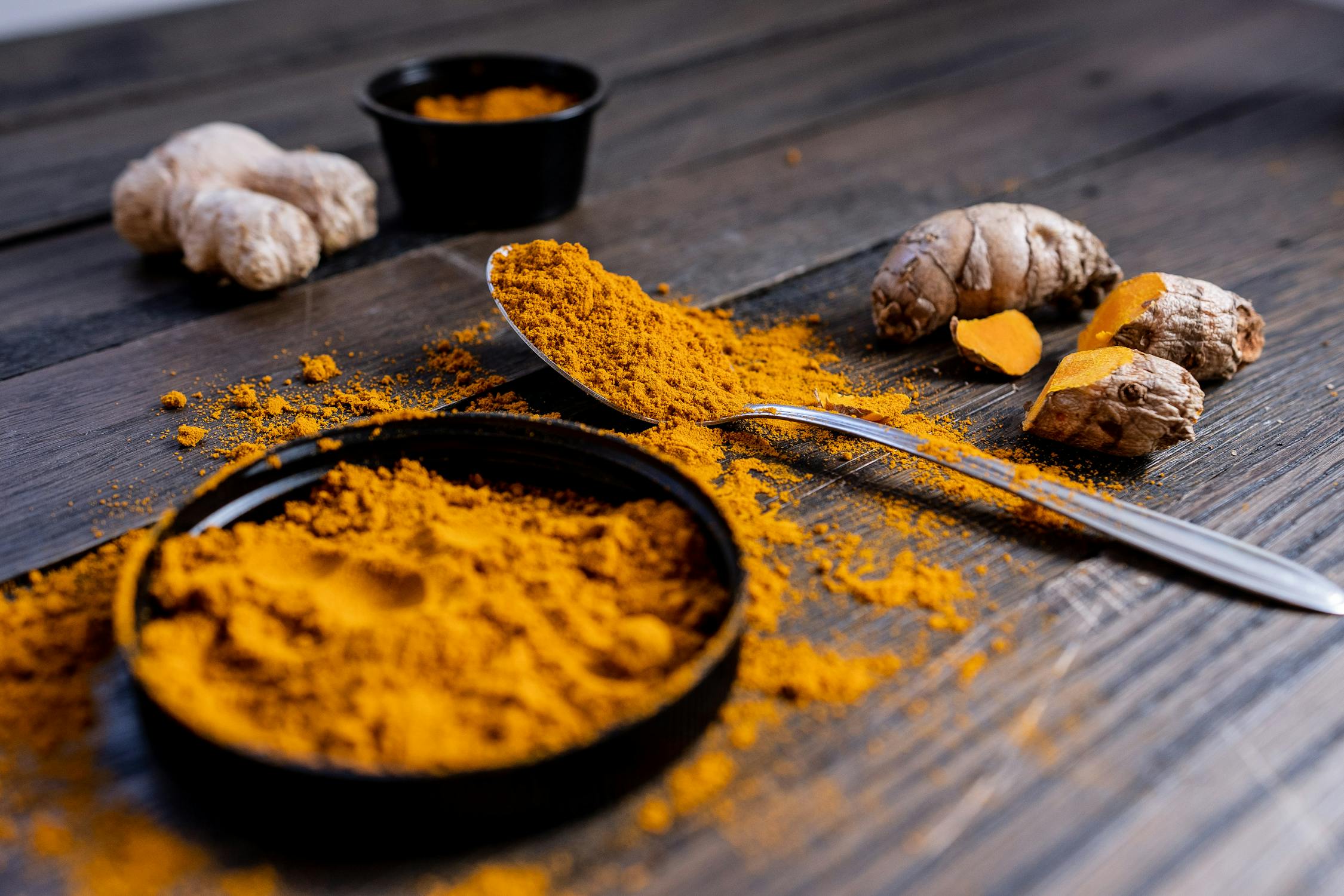 turmeric root and powder spread out on a dark table