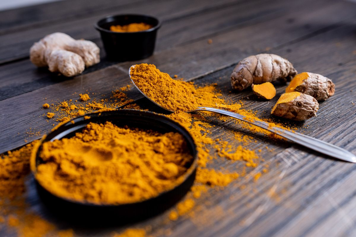 Vibrant turmeric powder and root arranged on a rustic wooden surface