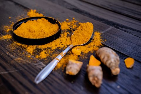 Turmeric powder and root with a spoon