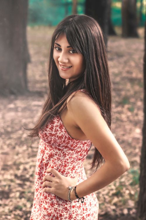 Free Beautiful woman in a floral dress posing in a sunlit forest, exuding elegance and warmth. Stock Photo