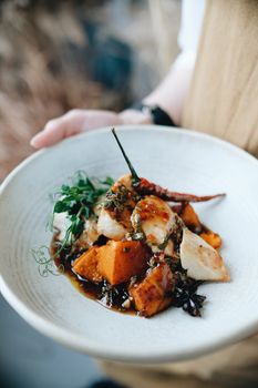Delicious roasted chicken served with vegetables in a rich sauce on a white plate.