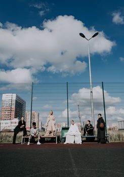 Fashionable group poses on an outdoor basketball court under a bright blue sky.