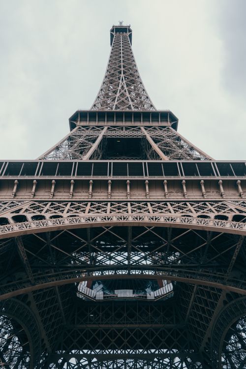 Free Dramatic low angle view of the iconic Eiffel Tower under a cloudy sky in Paris, France. Stock Photo