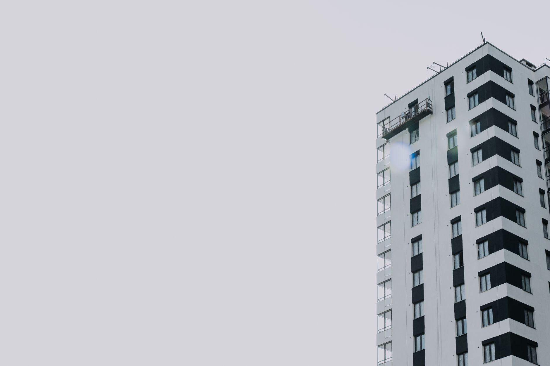Elegant high-rise residential building set against a clear sky, offering copy space