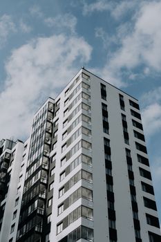 View of a contemporary high-rise building with symmetrical design against a blue sky with clouds.