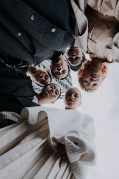Group of diverse people captured from below in stylish outfits, showcasing trendy fashion against a bright sky.