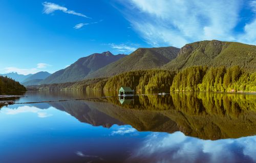 Free Serene mountain lake reflecting clear blue skies and dense forests. Stock Photo