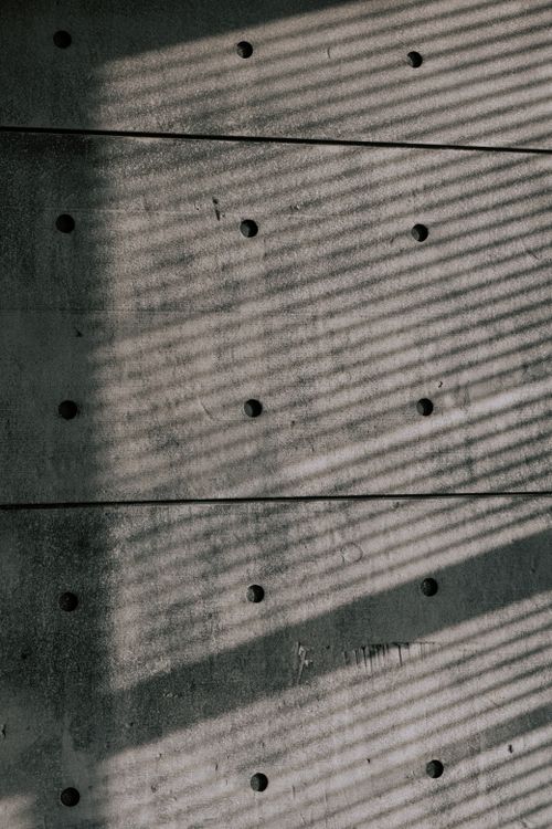 Free Abstract image of a textured concrete wall with striped shadows, creating an artistic look. Stock Photo