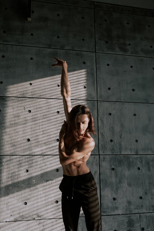 Free Man with Naked Torso Dancing near Concrete Wall Stock Photo