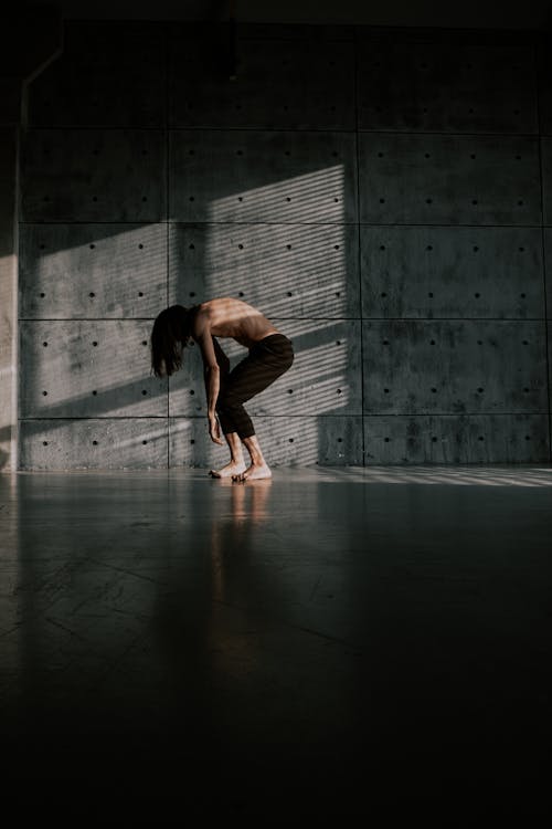 Free Man with Naked Torso Dancing near Concrete Wall Stock Photo