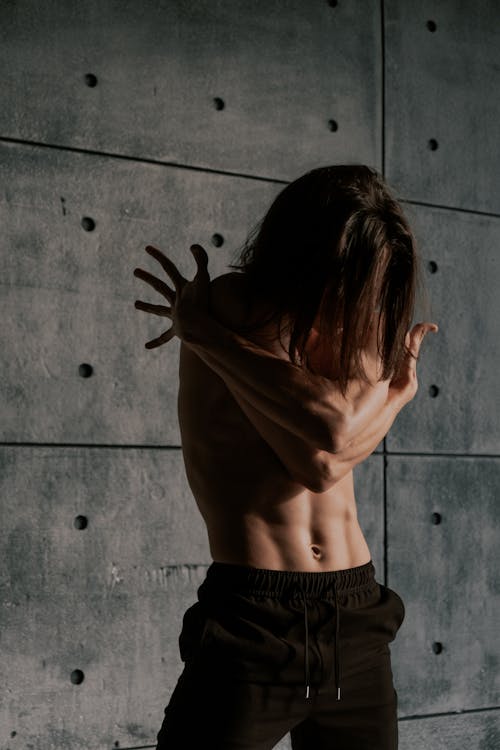 Free Man with Naked Torso Dancing near Concrete Wall Stock Photo