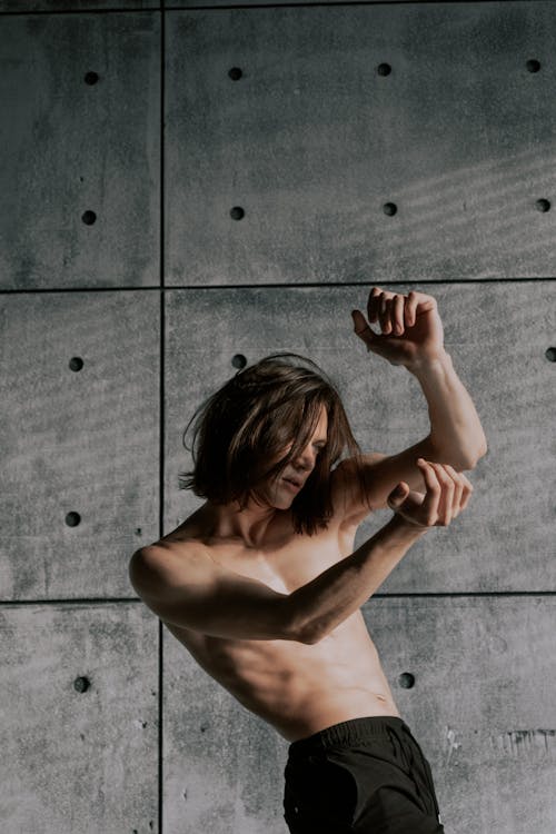 Free Man with Naked Torso Dancing near Concrete Wall Stock Photo