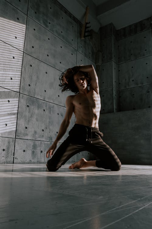 Free Man with Naked Torso Dancing near Concrete Wall Stock Photo