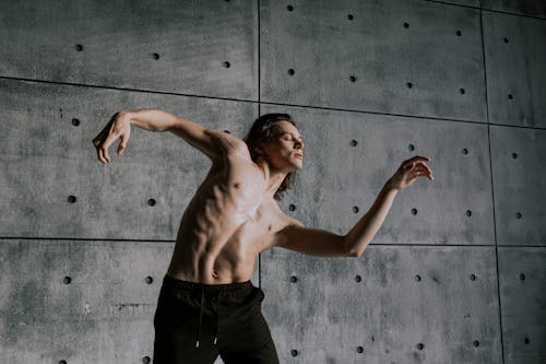 Man with Naked Torso Dancing near Concrete Wall