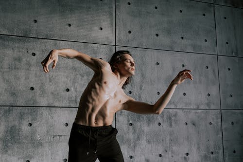 Free Man with Naked Torso Dancing near Concrete Wall Stock Photo