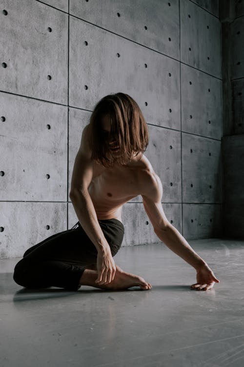 Free Man with Naked Torso Dancing near Concrete Wall Stock Photo