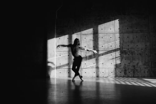 Free A shirtless dancer in motion casting shadows on a concrete wall. Stock Photo