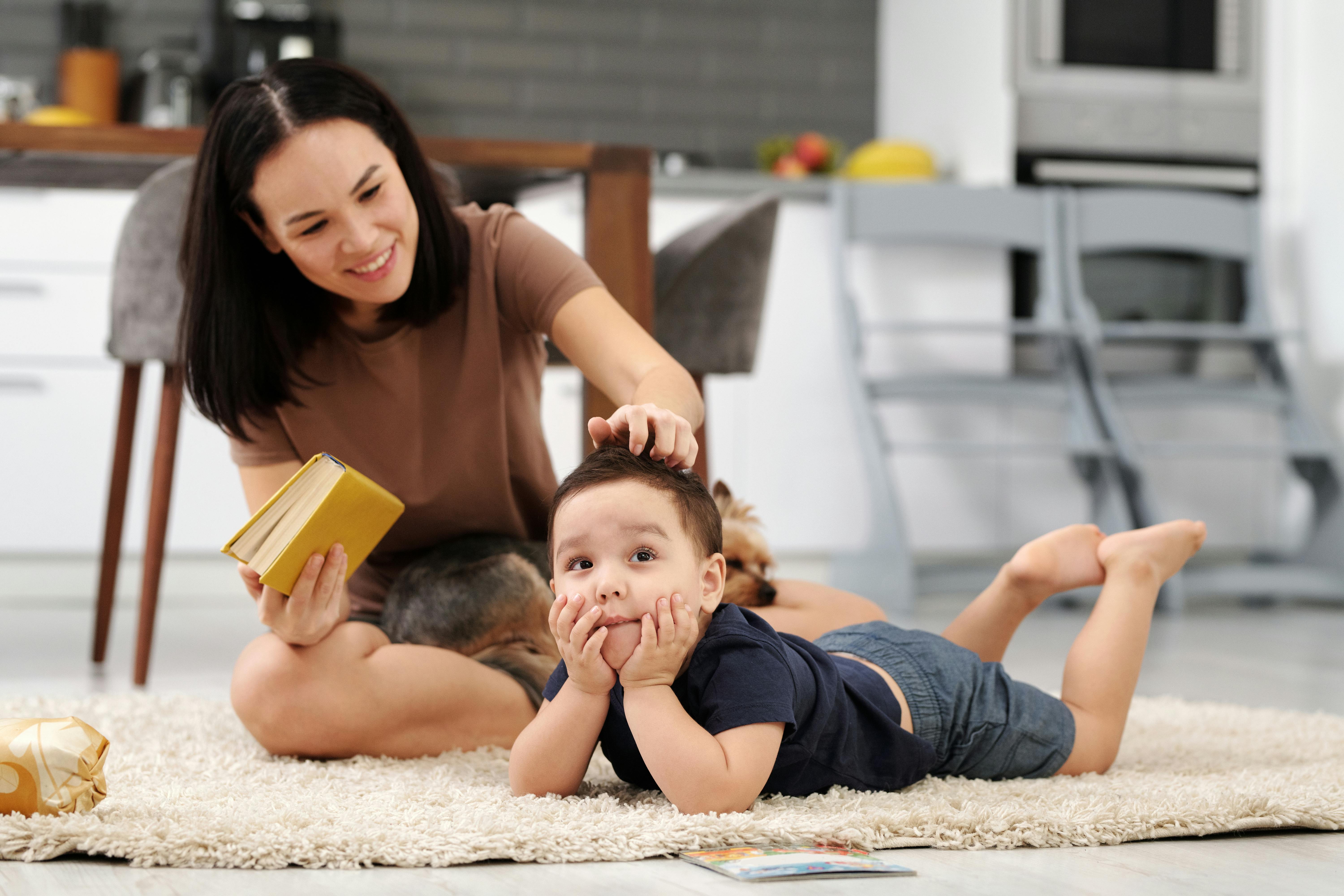 A mother and child bonding over a book while relaxing on the carpet in a cozy home setting.