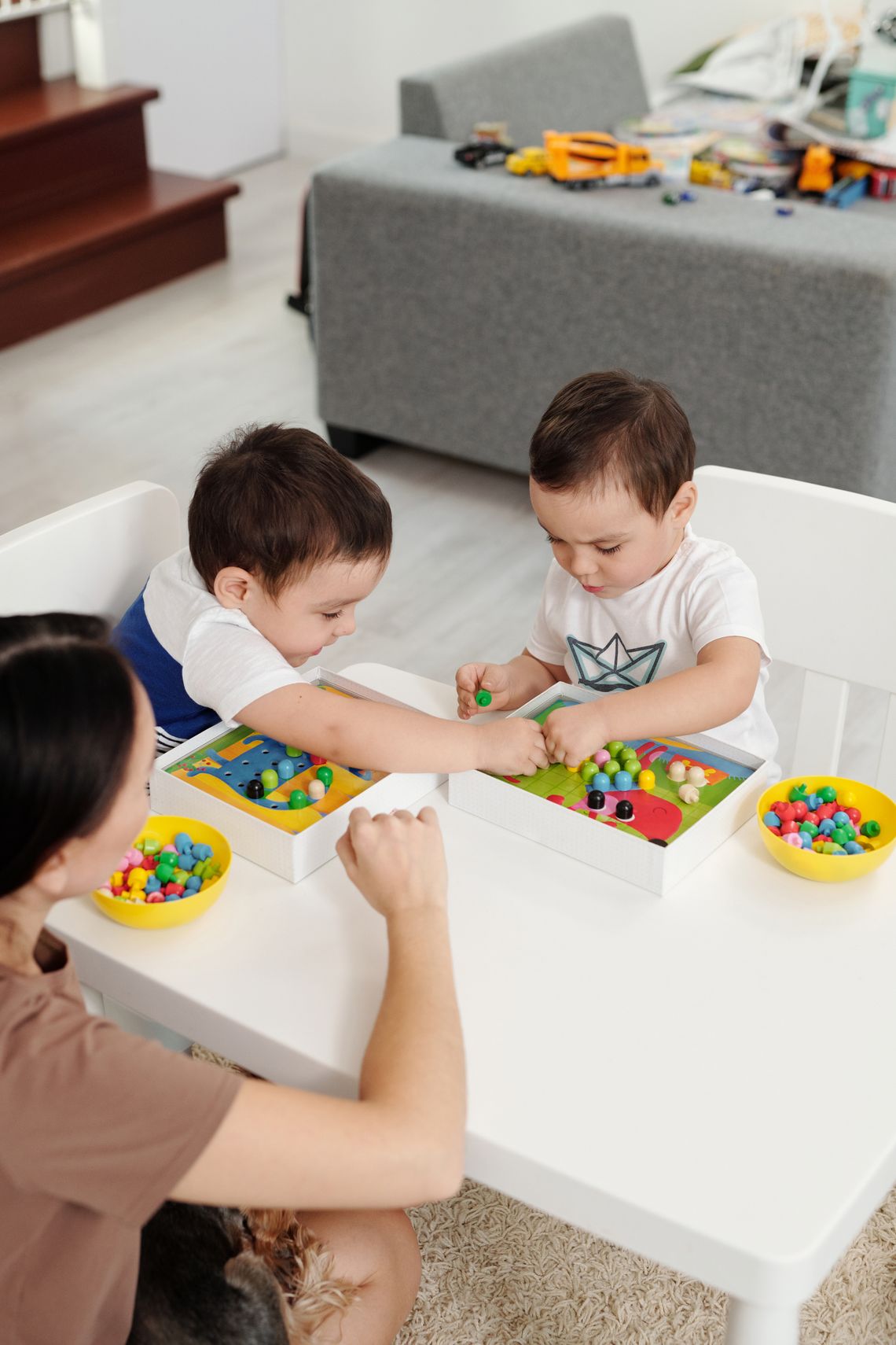 Parent supervising two young children during a colorful hands-on learning activity