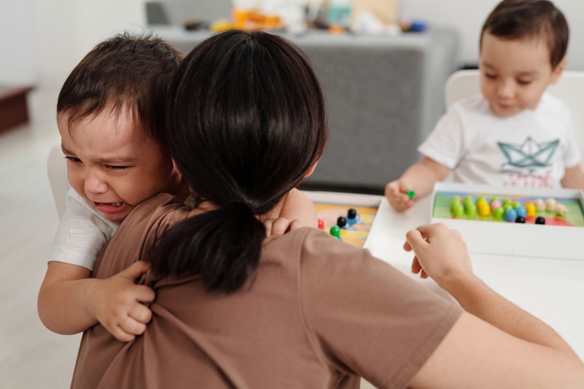 A parent comforting a crying child during an emotional moment at home