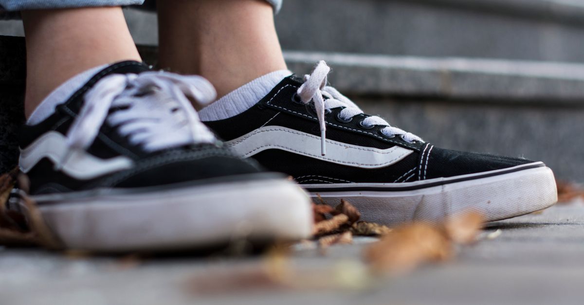 A close-up of black and white sneakers on stone steps, symbolizing casual style and comfort.
