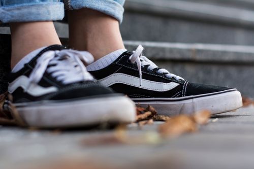 Free A close-up of black and white sneakers on stone steps, symbolizing casual style and comfort. Stock Photo