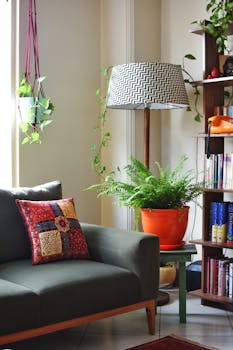 Stylish living room featuring a modern lamp, indoor plants, and a colorful pillow on a sofa.