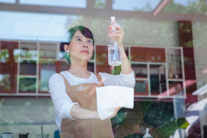 Cleaner wiping down glass in a commercial space