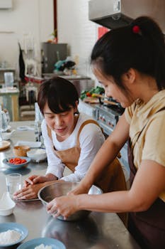Two Asian women prepare food together in a cozy kitchen, showcasing teamwork.