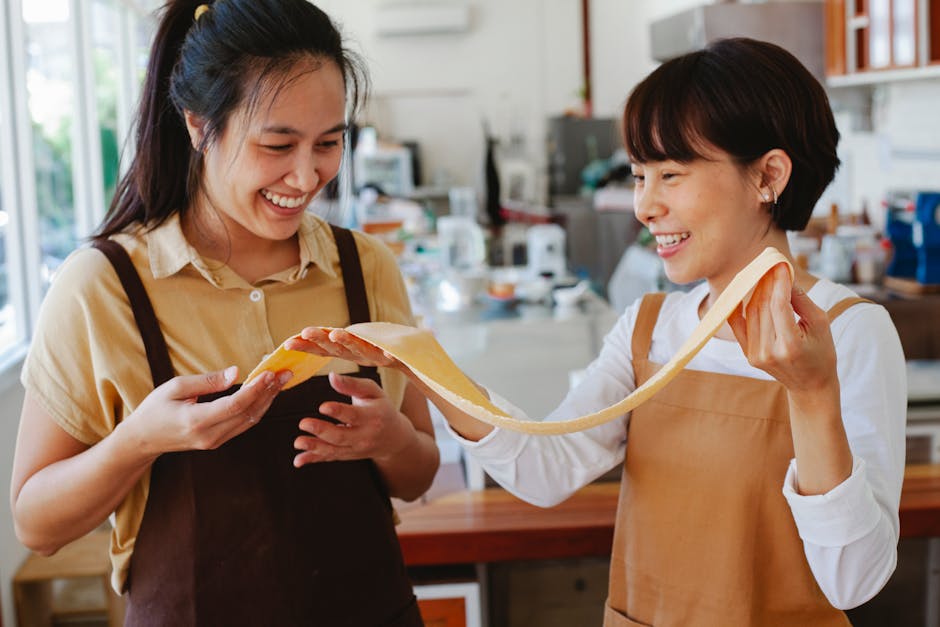 A group of people laughing and cooking together in a modern, well-equipped kitchen.