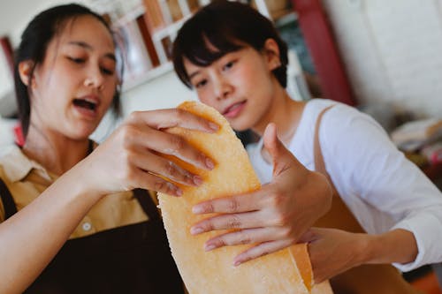 Close Up Photo of Women Holding a Dough
