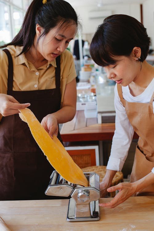 Woman Wearing Apron Putting Dough in Pasta Maker