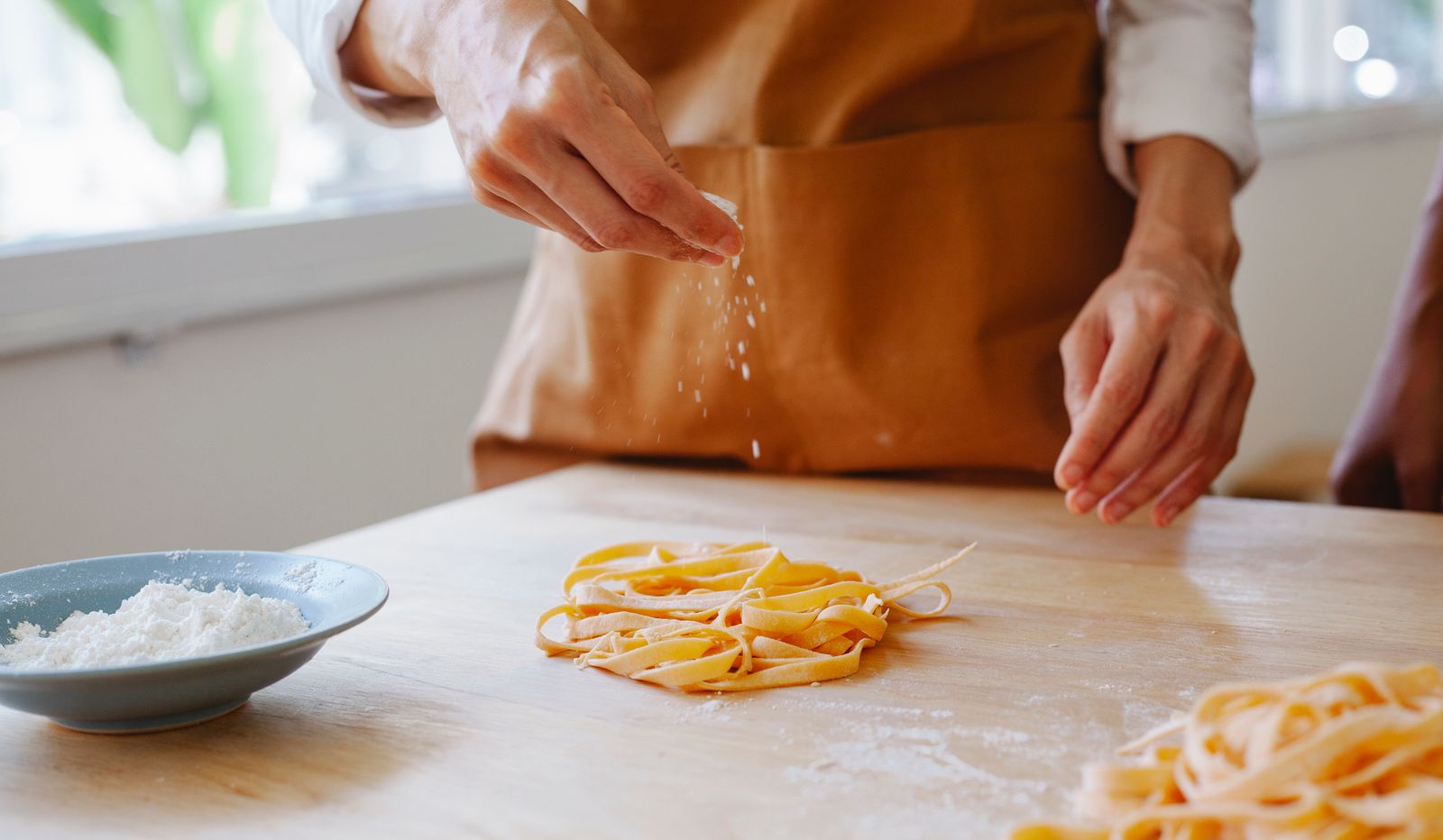Mani che infarinano tagliatelle fresche