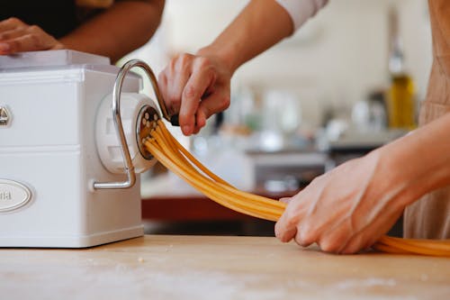 Person Cutting Pasta Using a Machine