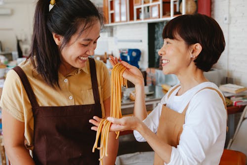 Woman Holding Noodles in Front of a Person