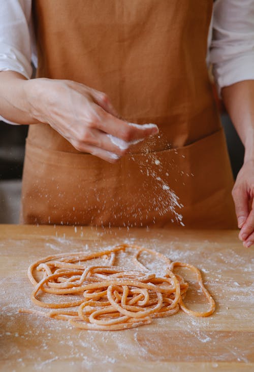 Photo of a Person Putting Flour on Pasta