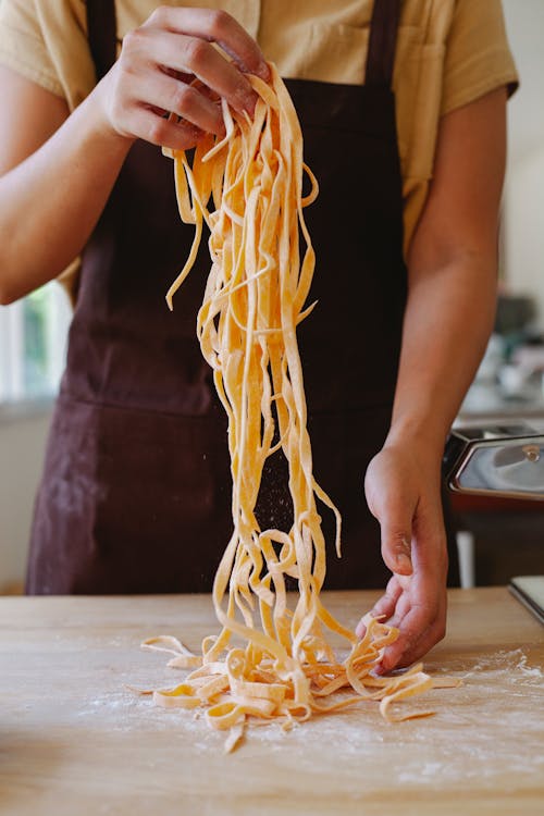 Person Wearing Apron Holding Pasta