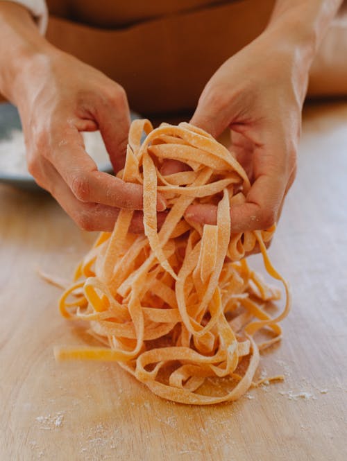 Close-Up Photo of a Person's Hands Holding Uncooked Pasta