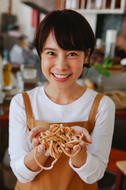 Photo of a Woman with Short Hair Showing Pasta to the Camera
