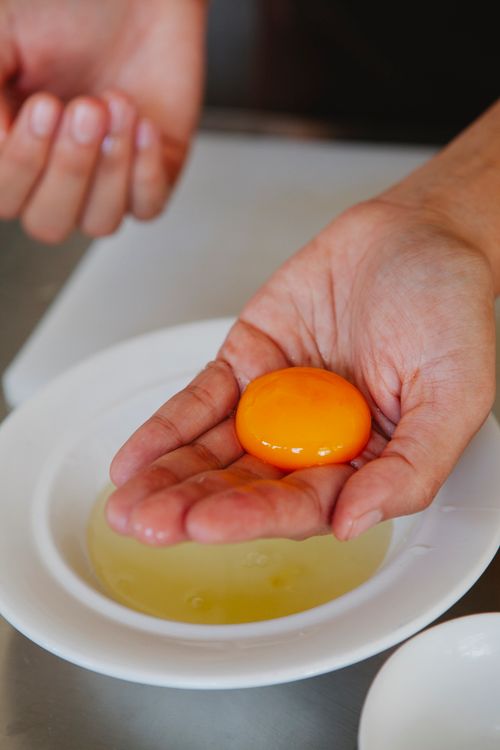 Free A vibrant egg yolk resting delicately in a hand, ideal for culinary themes. Stock Photo