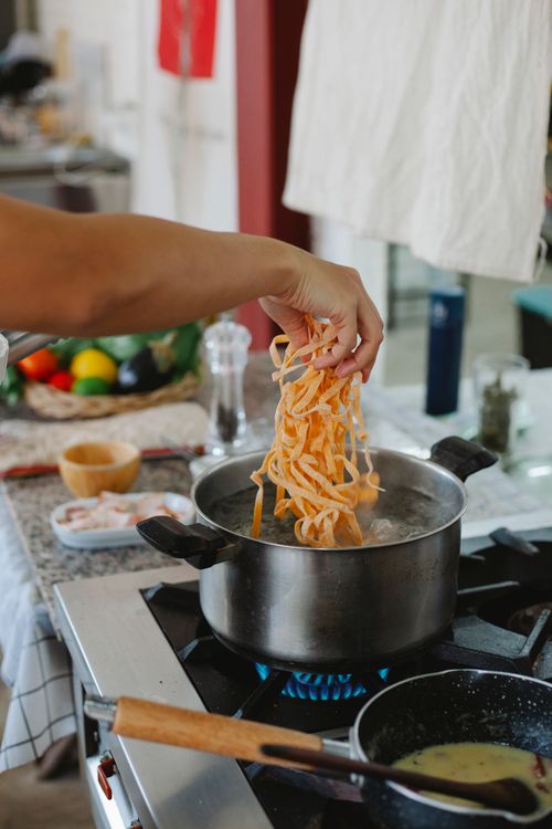 Free Fresh homemade pasta being cooked in a pot of boiling water in a modern kitchen. Stock Photo
