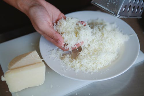 Close Up Shot of a Person Holding Grated Cheese
