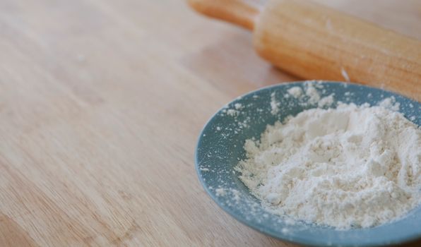 Close-up of flour in a bowl with a rolling pin, perfect for baking concepts.