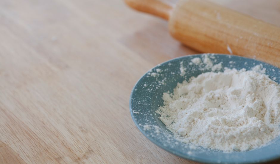 Close-up of flour in a bowl with a rolling pin, perfect for baking concepts.