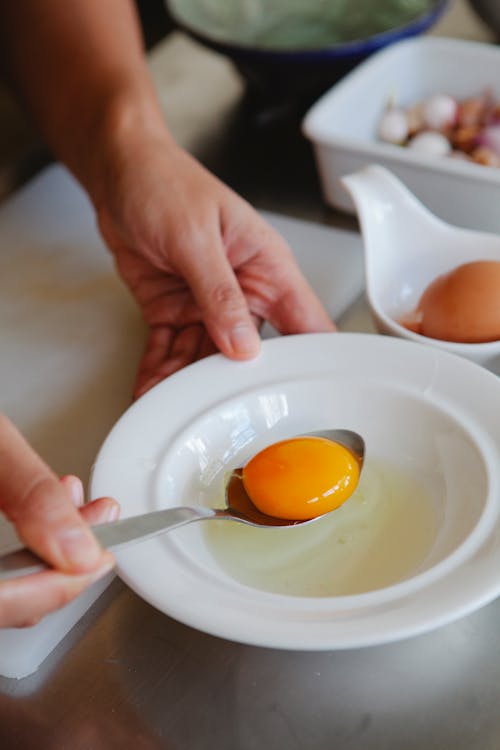 Close Up of Hands with Egg Yolk on Spoon