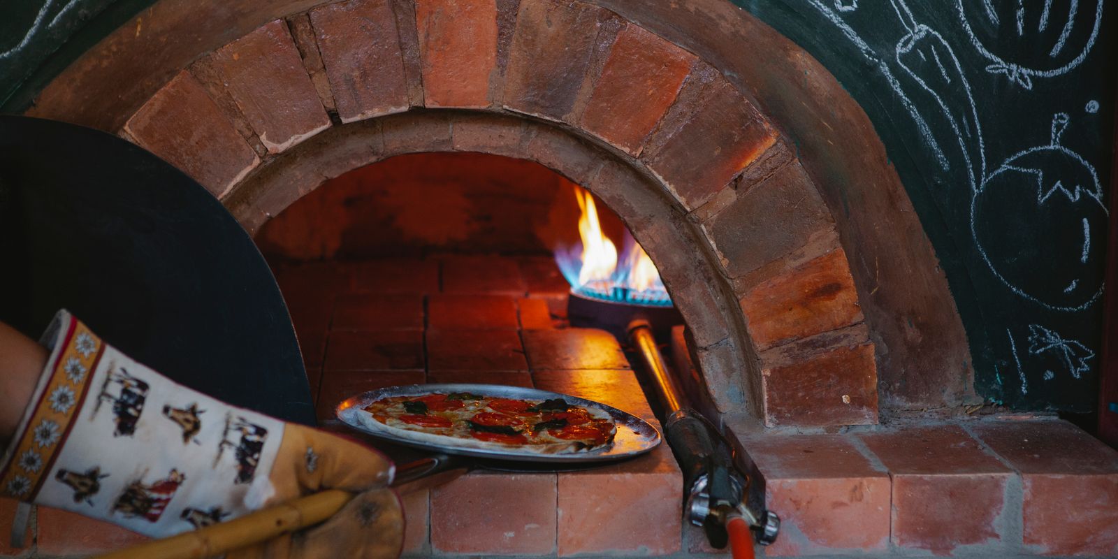 A pizza baking in a traditional wood-fired brick oven in a cozy pizzeria