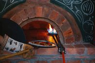 A delicious pizza baking in a traditional wood-fired brick oven in a cozy Italian pizzeria.