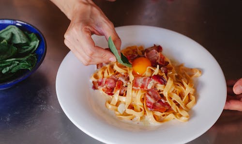 Hand Eating Pasta with Egg