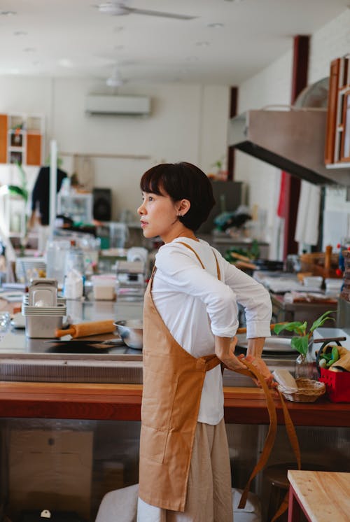 Woman Putting on Apron Before Cooking