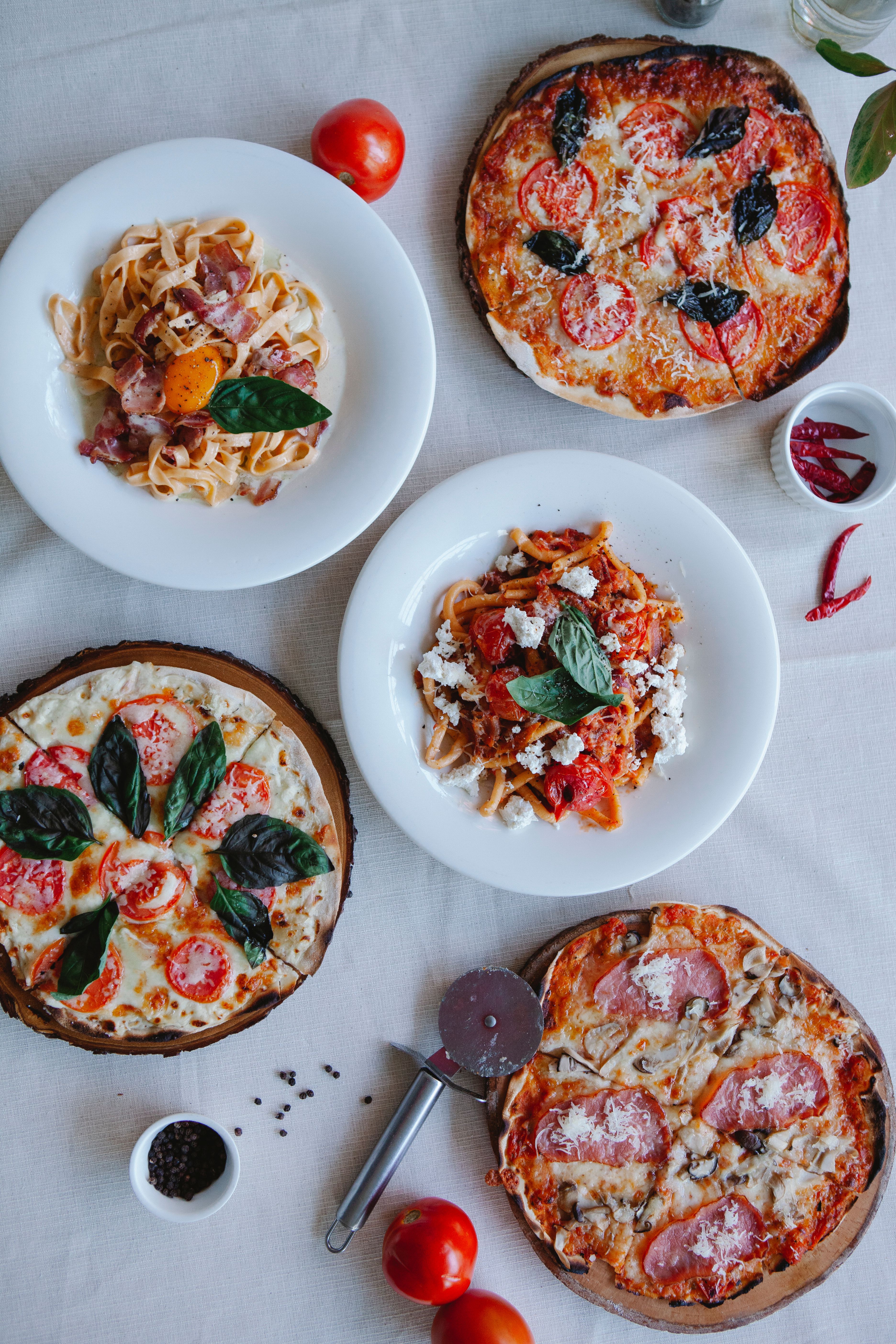 A tempting assortment of Italian pizzas and pasta dishes arranged beautifully on a table.